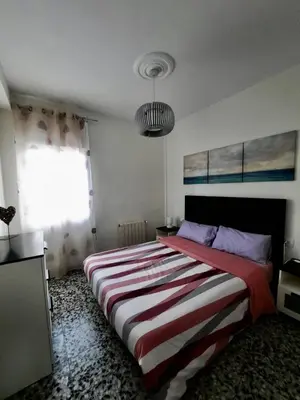 a bedroom with a large bed with a striped blanket at Piso en la playa in Valencia