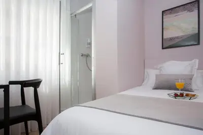 a white bedroom with a bed and a chair at Palacios Rooms in Valencia