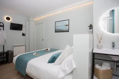 a white bedroom with a bed and a sink at Palacios Rooms in Valencia