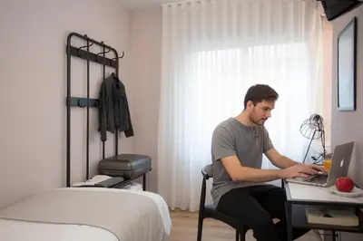a man sitting at a desk with a laptop in a bedroom at Palacios Rooms in Valencia