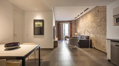 a living room with a table and chairs and a brick wall at Mon Suites San Martin in Valencia