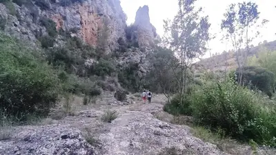 two people walking down a dirt path through a mountain at Casa Las Violetas in Altura