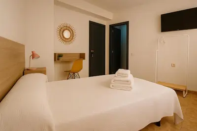 a bedroom with a white bed with towels on it at Rooms Avenida in Tavernes de Valldigna