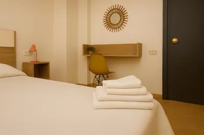 a bedroom with a bed and a chair and a mirror at Rooms Avenida in Tavernes de Valldigna