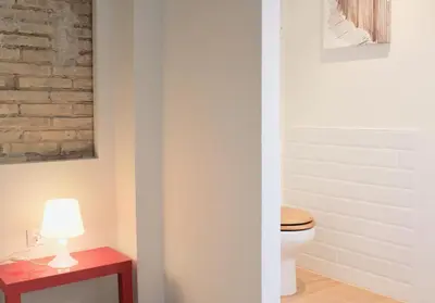 a bathroom with a toilet and a table with a lamp at Apartamento Con Vistas Espectaculares in Valencia