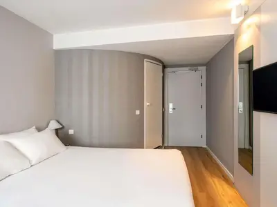 a bedroom with a bed and a desk and a red chair at Ibis Valencia Alfafar in Alfafar