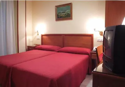 a bedroom with a red bed and a tv at Hotel Isabel in Almussafes
