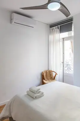 a bedroom with a bed with a fan and a chair at Casa Marcellino Valencia Centro in Valencia