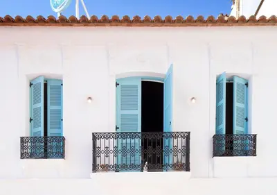 a white building with blue shutters and a balcony at Apartamentos La más Bonita in Valencia
