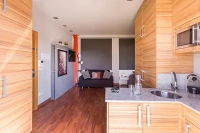 a kitchen with wooden cabinets and a living room at Sky Touristic Attic in Valencia