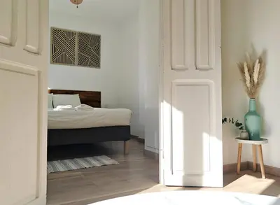 a white bedroom with a bed and a table at Hola Valencia - Holiday Apartments in Valencia