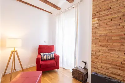 a living room with a red chair and a brick wall at FLORIT FLATS - Charming Ruzafa Apartment & Terrace in Valencia