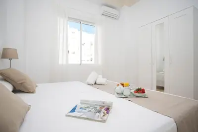 a white bedroom with a bed with a magazine on it at Antiguo Reino Apartment in Valencia
