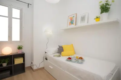 a white room with a bed with a yellow chair at Antiguo Reino Apartment in Valencia