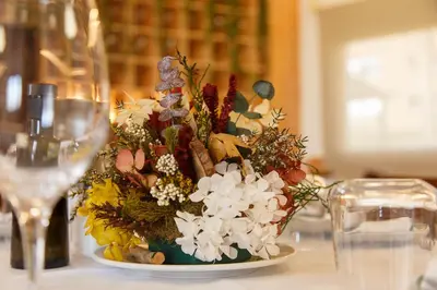 a vase of flowers on a table with a wine glass at La Orza de Angel in Chiva