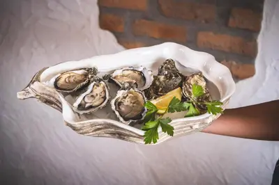 a person holding a bowl of oysters on a table at La Orza de Angel in Chiva