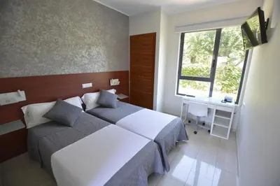a bedroom with a bed and a desk and a window at Hotel Vista al Sol in Paterna