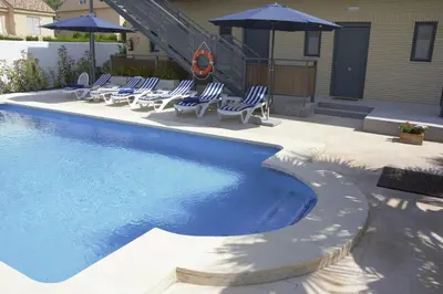 a swimming pool with chairs and umbrellas next to a house at Hotel Vista al Sol in Paterna