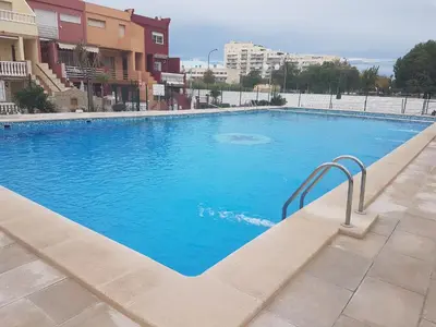 a large blue swimming pool next to some buildings at Dúplex, piscina y playa in Puebla de Farnals