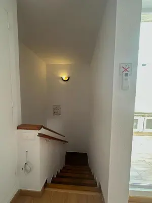 a hallway with a staircase with a light on the wall at Dúplex, piscina y playa in Puebla de Farnals