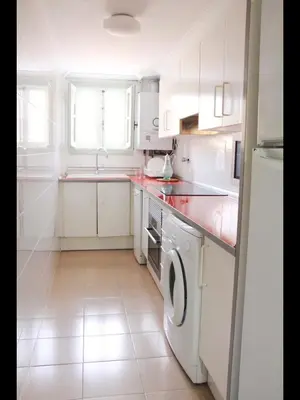 a kitchen with white cabinets and a washer and dryer at Cozy apartment on the sea in Port Saplaya