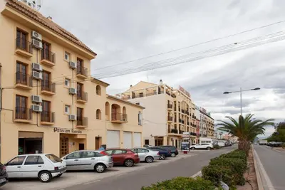 a row of cars parked on a street next to buildings at Olympia Ronda Hostel in El Puig