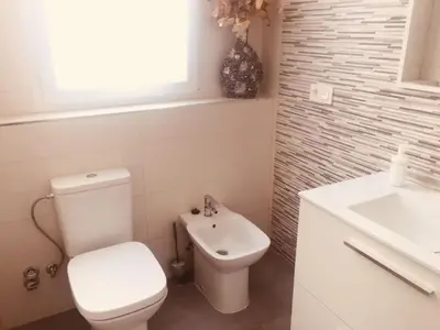 a white bathroom with a toilet and a sink at Piso céntrico Plaza Toros in Valencia