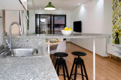 a kitchen with a sink and a counter with stools at ApartUP Patacona Attic I in Valencia