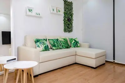 a living room with a white couch with green pillows at ApartUP Patacona Attic I in Valencia
