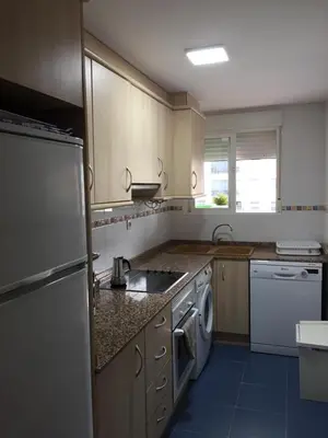 a kitchen with a white refrigerator and a dishwasher at Apartamentos Playa de Moncofa in Moncófar