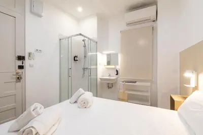a white bathroom with a bed with towels on it at Pensión Alicante by Moontels in Valencia