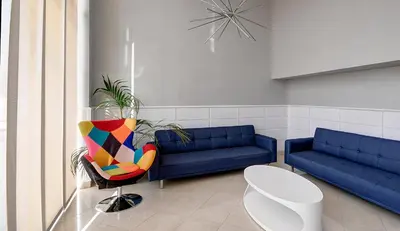 a waiting room with a blue couch and a colorful chair at Hotel Vila-real Azul in Villareal