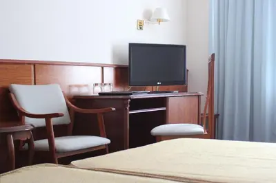 a hotel room with a tv on a desk with two chairs at Hotel Vila-real Palace in Villareal