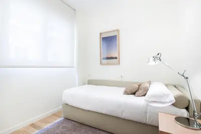 a white bedroom with a bed and a lamp at City Center Atico 360 in Valencia