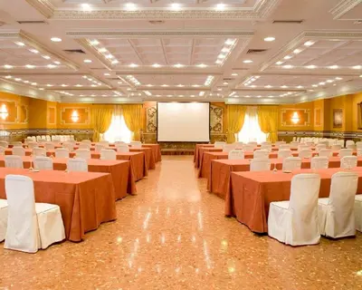 a banquet hall with tables and white chairs and a screen at Casa Quiquet in Beniparrell