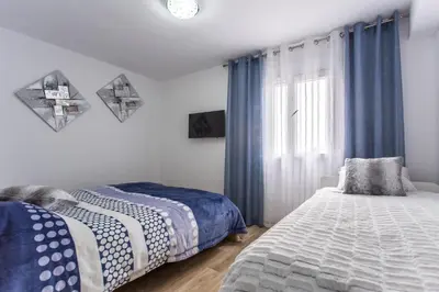 a bedroom with two beds and a window with blue curtains at Versus Apartments near City of Arts 2 in Valencia
