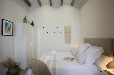 a white room with a white bed with pillows at SingularStays Parque Central in Valencia