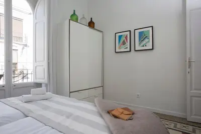 a white bedroom with a bed and a large window at SingularStays Parque Central in Valencia