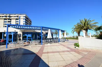 a patio with chairs and umbrellas in front of a building at Apartamento frente al mar in Valencia