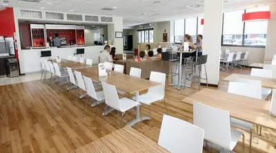 a restaurant with wooden tables and white chairs at Travelodge Valencia Aeropuerto in Manises