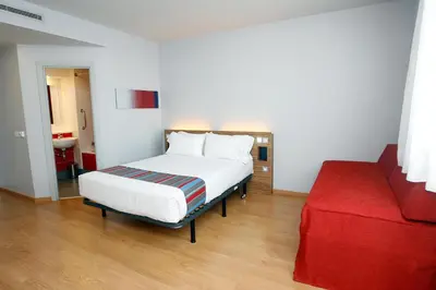 a bedroom with a bed and a red couch at Travelodge Valencia Aeropuerto in Manises