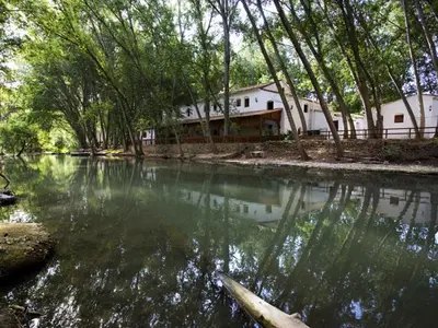 a house sitting next to a river with trees at Molino Galán in Alborache