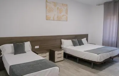 a bedroom with two beds and a picture on the wall at Hostal Tartessos in Valencia