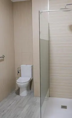a bathroom with a toilet and a glass shower door at Hostal Tartessos in Valencia