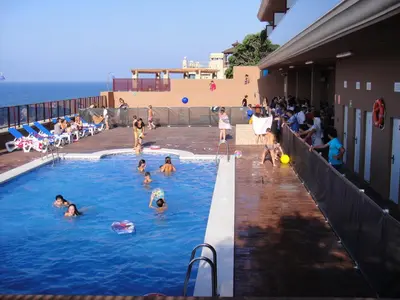 a group of people in a swimming pool near the ocean at Aparthotel El Faro in Cullera