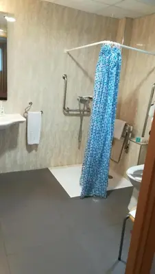 a bathroom with a blue shower curtain on the floor at Aparthotel El Faro in Cullera
