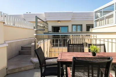 a patio with a wooden table and chairs on a balcony at ApartUP Patacona Terrace Duplex I in Valencia