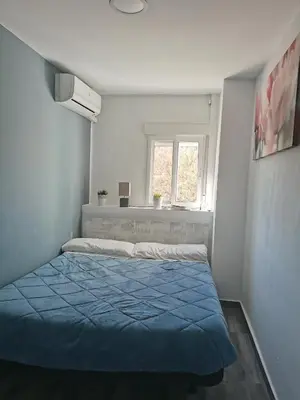 a bedroom with a blue bed and a window at Plaza Sainetero in Valencia