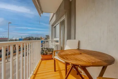 a wooden table and chair on a balcony with a window at 1ªLinea de playa Puerto de Sagunto in Puerto de Sagunto