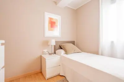 a white bedroom with a bed and a lamp on a night stand at 1ªLinea de playa Puerto de Sagunto in Puerto de Sagunto